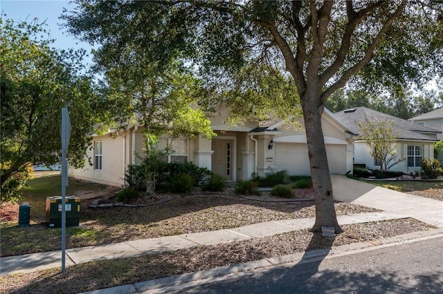 ranch-style home featuring a garage, concrete driveway, and stucco siding