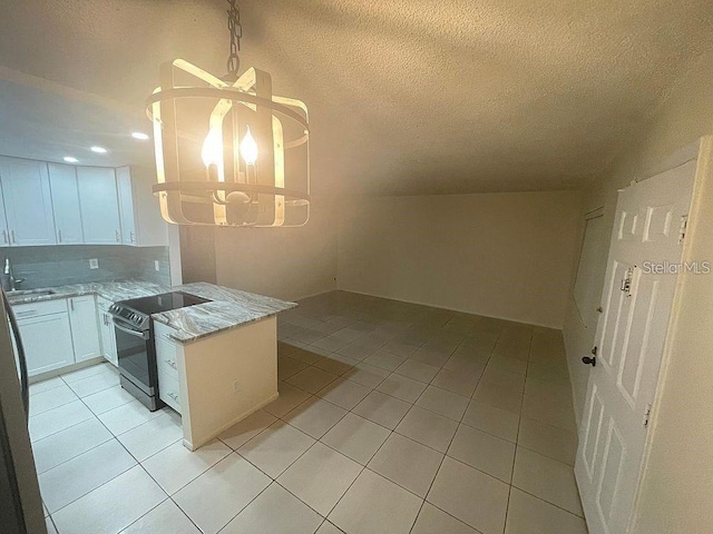 kitchen with light tile patterned floors, a peninsula, white cabinets, stainless steel range with electric cooktop, and light stone countertops