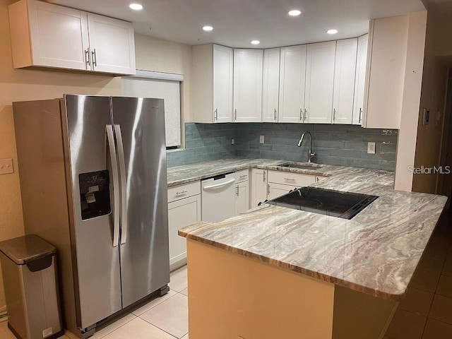 kitchen with a peninsula, white cabinetry, light stone counters, and a sink