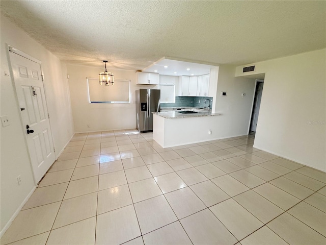 3300 Fox Chase Cir N Unit 229, Palm Harbor, FL 34683 - kitchen with stainless steel refrigerator with ice dispenser, light tile patterned flooring, a textured ceiling, white cabinetry, and a peninsula