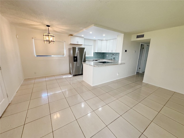 3300 Fox Chase Cir N Unit 229, Palm Harbor, FL 34683 - kitchen featuring stainless steel fridge with ice dispenser, light tile patterned flooring, a peninsula, white cabinetry, and a textured ceiling