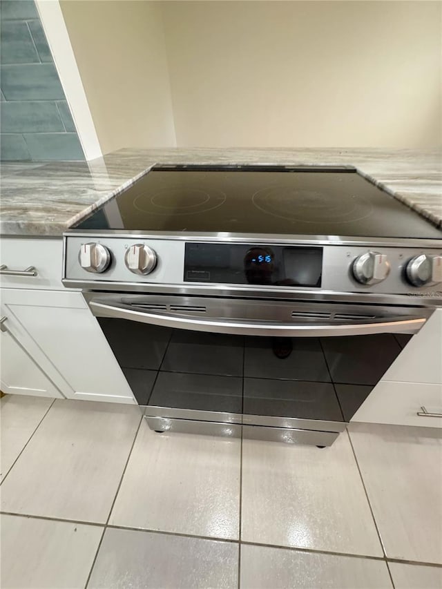 3300 Fox Chase Cir N Unit 229, Palm Harbor, FL 34683 - kitchen view of stainless steel range with electric stovetop, white cabinets, and light stone counters