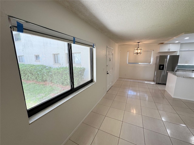 3300 Fox Chase Cir N Unit 229, Palm Harbor, FL 34683 - spare room with a textured ceiling, light tile patterned floors, a chandelier, and baseboards