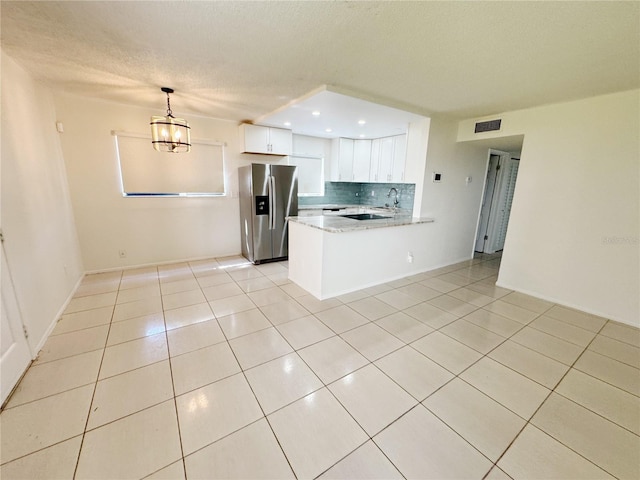3300 Fox Chase Cir N Unit 229, Palm Harbor, FL 34683 - kitchen featuring stainless steel refrigerator with ice dispenser, light tile patterned floors, a peninsula, white cabinets, and a textured ceiling