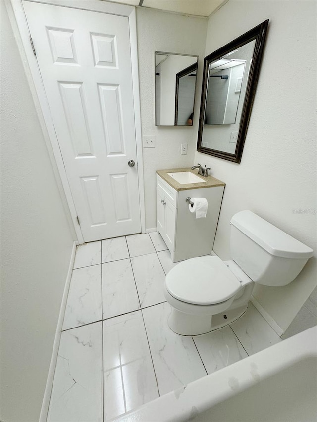 3300 Fox Chase Cir N Unit 229, Palm Harbor, FL 34683 - bathroom featuring marble look tiles, toilet, vanity, and baseboards