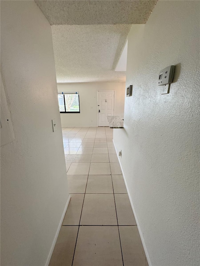 3300 Fox Chase Cir N Unit 229, Palm Harbor, FL 34683 - hall featuring a textured wall, light tile patterned floors, baseboards, and a textured ceiling