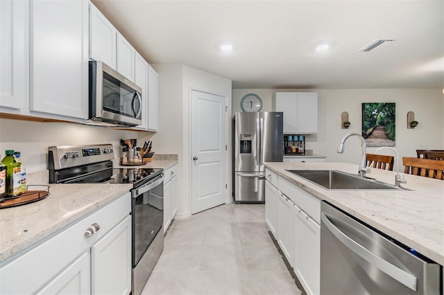 kitchen featuring stainless steel appliances, a sink, visible vents, and light stone countertops