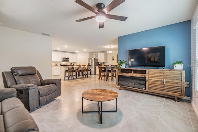 living room featuring baseboards, visible vents, a ceiling fan, light tile patterned flooring, and recessed lighting