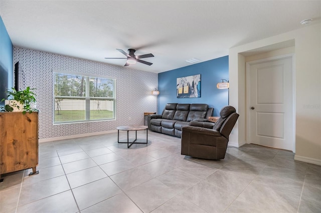 living area with wallpapered walls, baseboards, visible vents, ceiling fan, and an accent wall