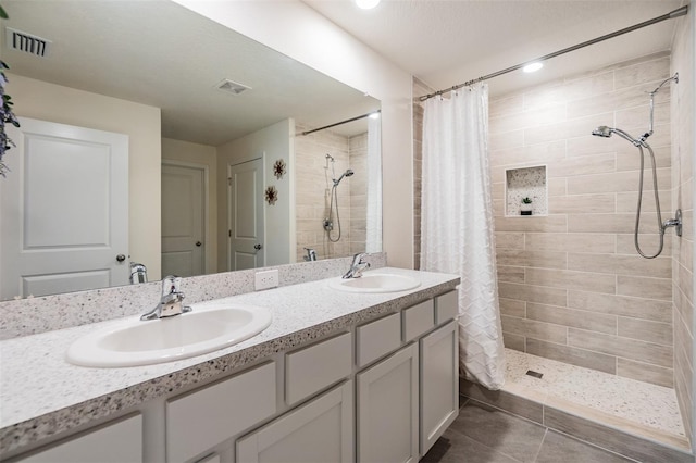 full bath with a tile shower, a sink, and visible vents