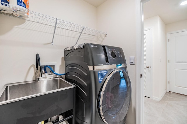 laundry area featuring laundry area, washing machine and clothes dryer, a sink, and tile patterned floors