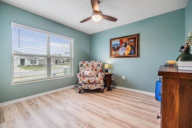 sitting room with a ceiling fan, baseboards, and wood finished floors