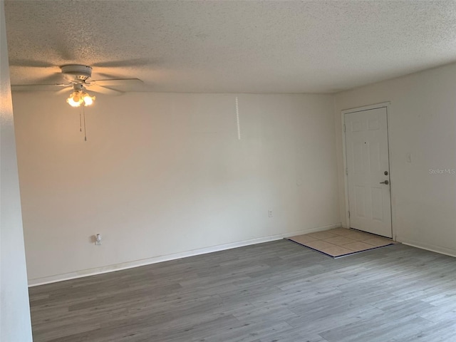 unfurnished room featuring wood finished floors, a ceiling fan, and a textured ceiling