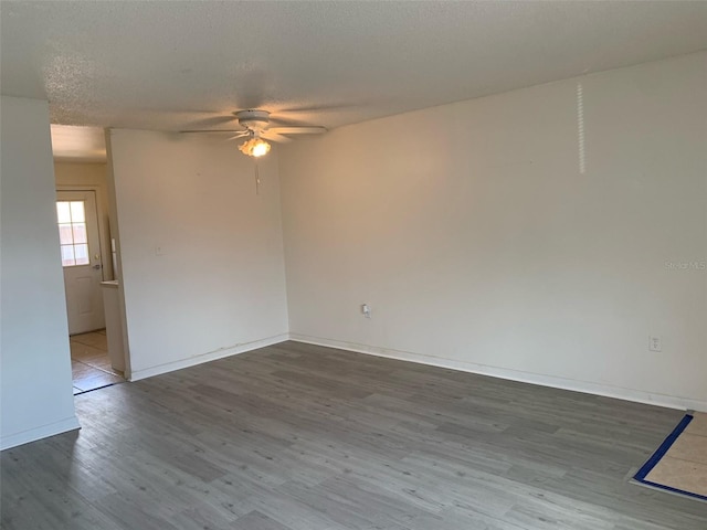 empty room featuring baseboards, a textured ceiling, a ceiling fan, and wood finished floors