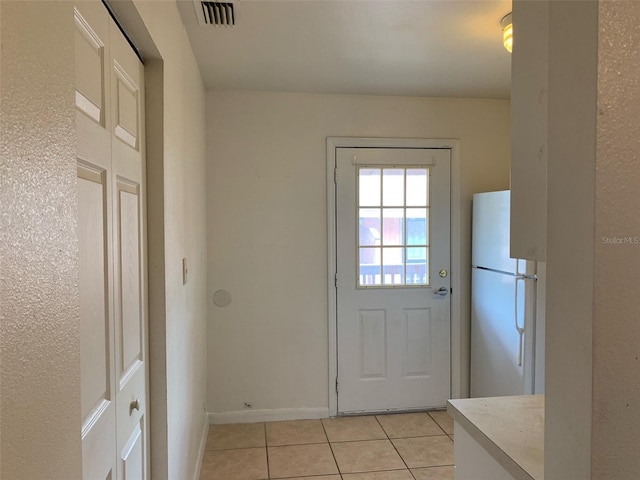 doorway with light tile patterned floors, baseboards, and visible vents