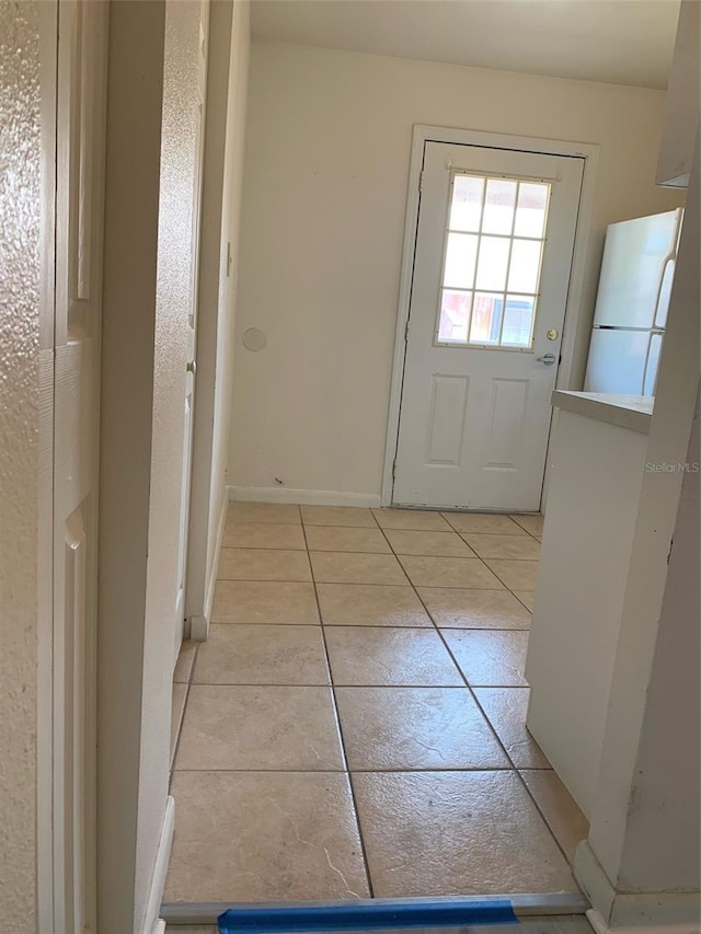 doorway to outside featuring light tile patterned floors and baseboards