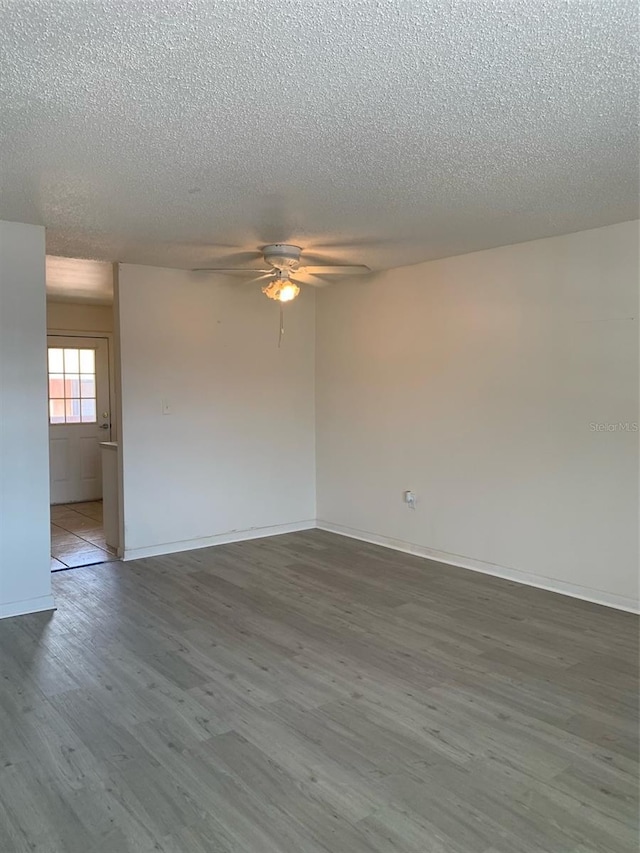 unfurnished room with baseboards, a textured ceiling, ceiling fan, and wood finished floors