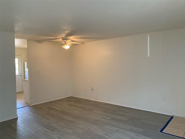 spare room with baseboards, wood finished floors, a textured ceiling, and ceiling fan