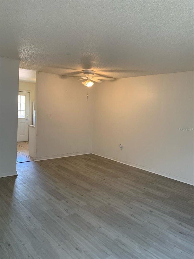 empty room with wood finished floors, a textured ceiling, and ceiling fan