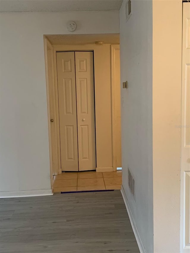 corridor featuring light wood-style floors, visible vents, and baseboards