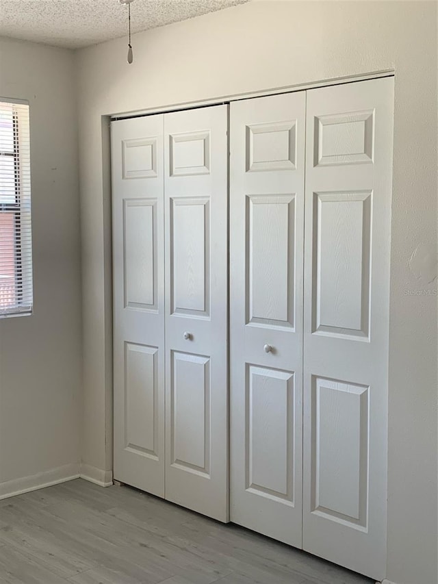 details featuring a textured ceiling, baseboards, and wood finished floors