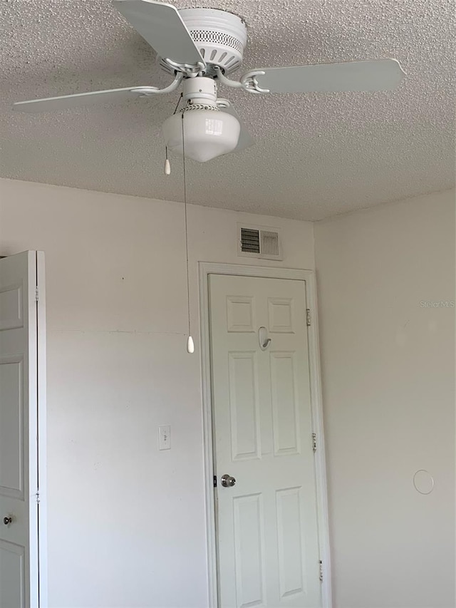 empty room with visible vents, a textured ceiling, and a ceiling fan