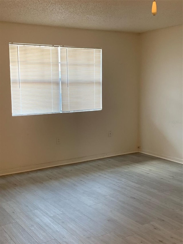 unfurnished room with baseboards and a textured ceiling