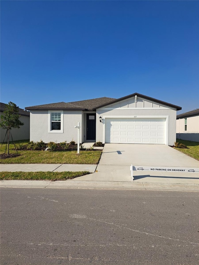 view of front of house with a front yard, driveway, an attached garage, and stucco siding