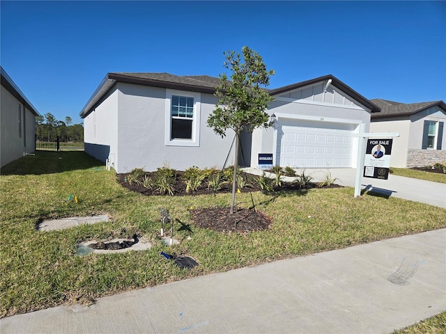 single story home with a garage, concrete driveway, a front yard, board and batten siding, and stucco siding