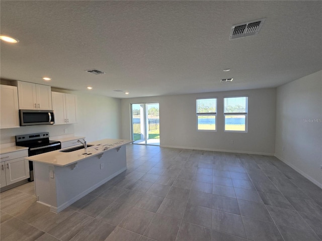 kitchen featuring stainless steel appliances, a kitchen island with sink, open floor plan, and visible vents