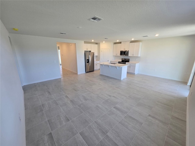 kitchen with white cabinetry, open floor plan, light countertops, appliances with stainless steel finishes, and an island with sink