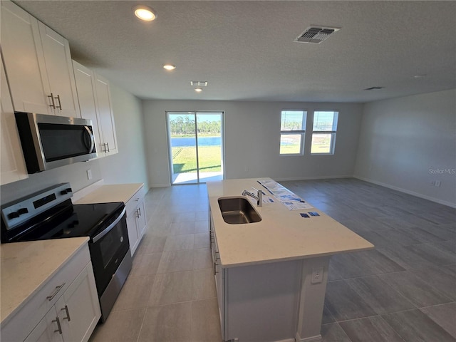 kitchen featuring a center island with sink, stainless steel appliances, visible vents, open floor plan, and a sink