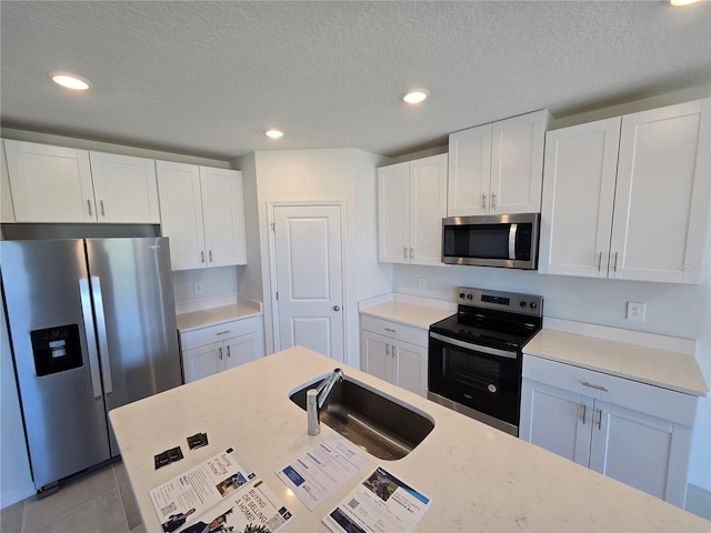 kitchen featuring recessed lighting, appliances with stainless steel finishes, white cabinetry, a sink, and light tile patterned flooring