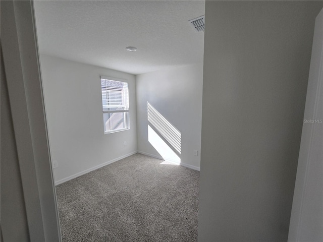 spare room with baseboards, a textured ceiling, visible vents, and carpet flooring