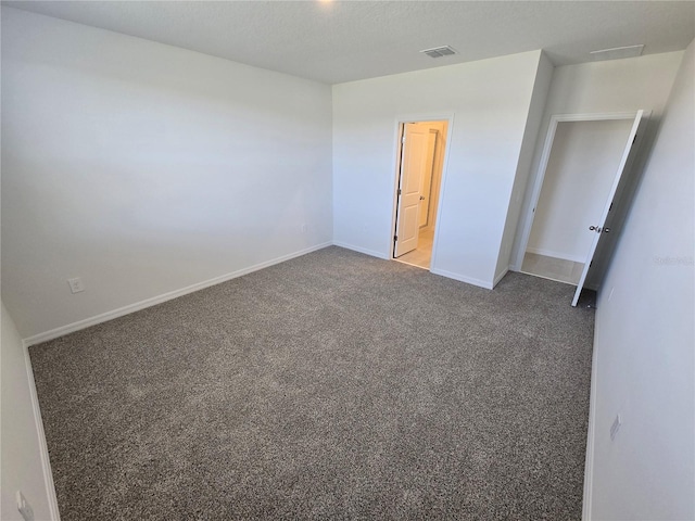 unfurnished bedroom featuring carpet floors, visible vents, a textured ceiling, and baseboards