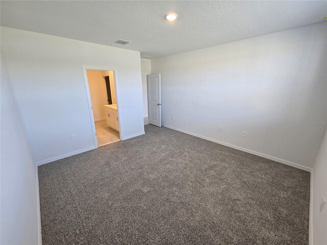 unfurnished bedroom with a textured ceiling, baseboards, visible vents, and light colored carpet