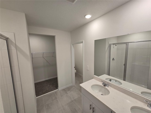 bathroom with a stall shower, a walk in closet, a sink, and toilet