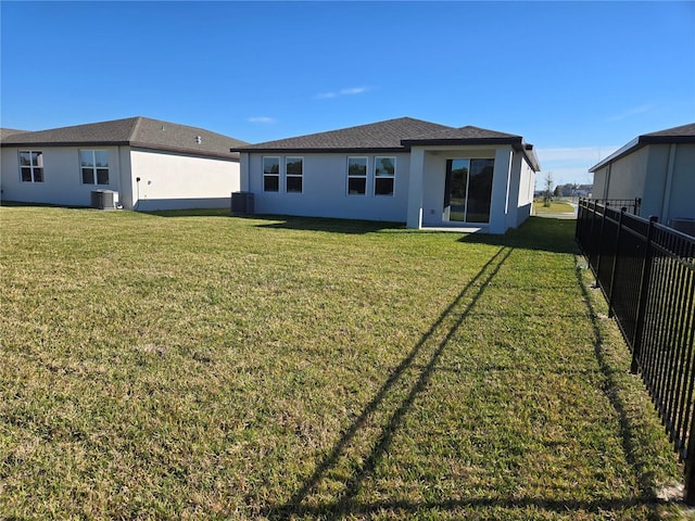 back of property featuring a yard, stucco siding, fence, and central air condition unit