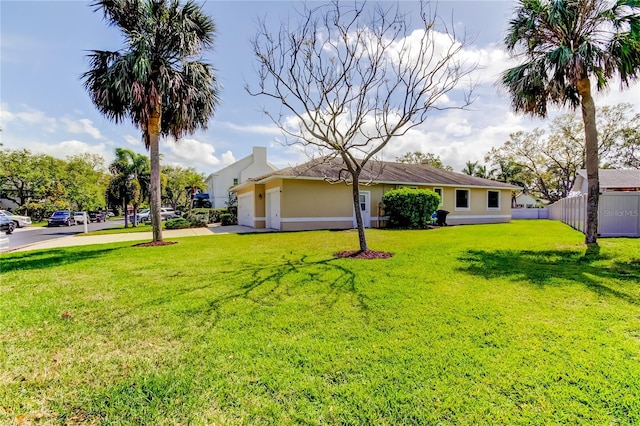 view of yard featuring a garage, concrete driveway, and fence