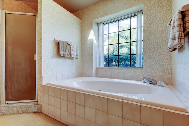 bathroom with a shower stall, a bath, and wallpapered walls