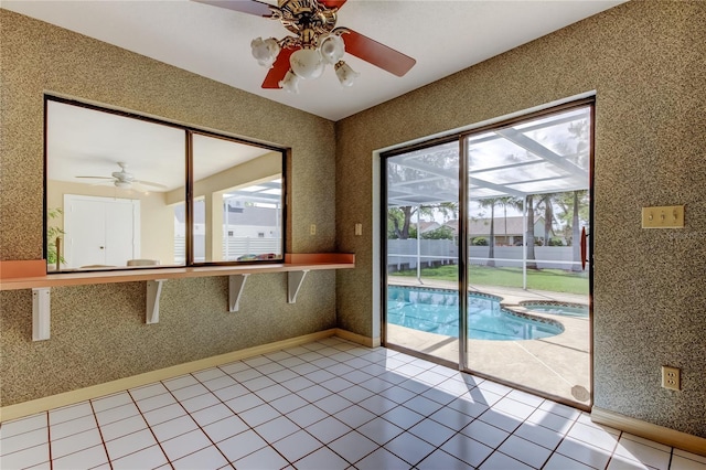 interior space with wallpapered walls, baseboards, and a ceiling fan