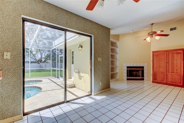 unfurnished living room with light tile patterned floors, visible vents, a sunroom, built in shelves, and a fireplace