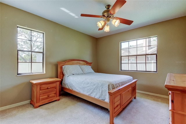 bedroom featuring multiple windows, baseboards, and light colored carpet