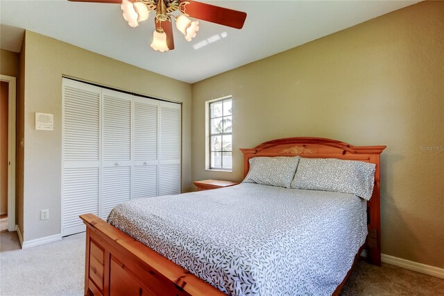 carpeted bedroom with a ceiling fan, a closet, and baseboards