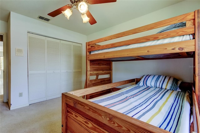 bedroom with ceiling fan, a closet, visible vents, and light colored carpet