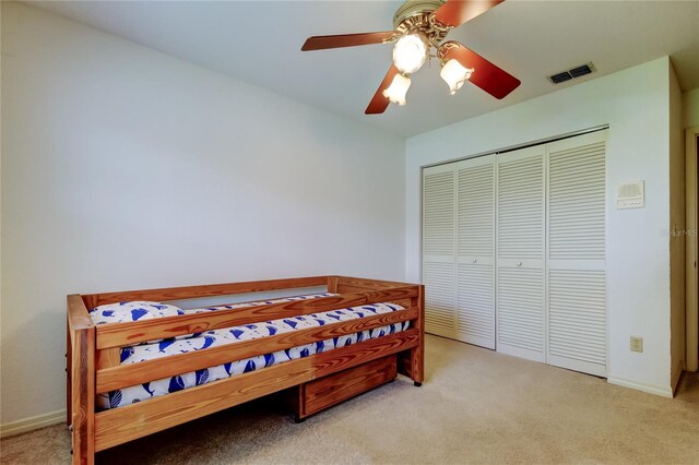 bedroom featuring a closet, light colored carpet, visible vents, and baseboards