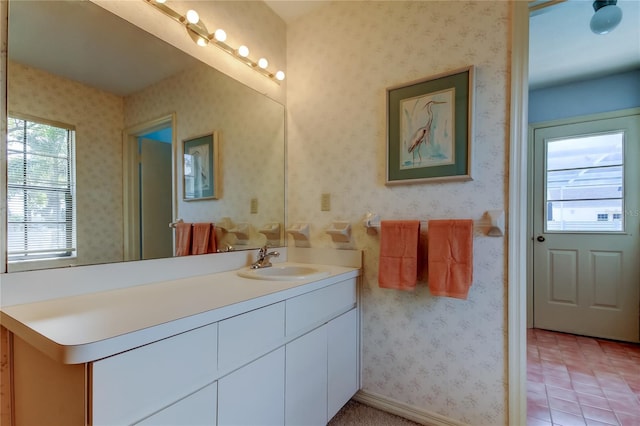 bathroom with baseboards, tile patterned floors, vanity, and wallpapered walls