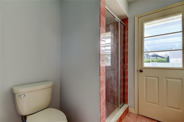 bathroom featuring tile patterned flooring, a shower stall, and toilet