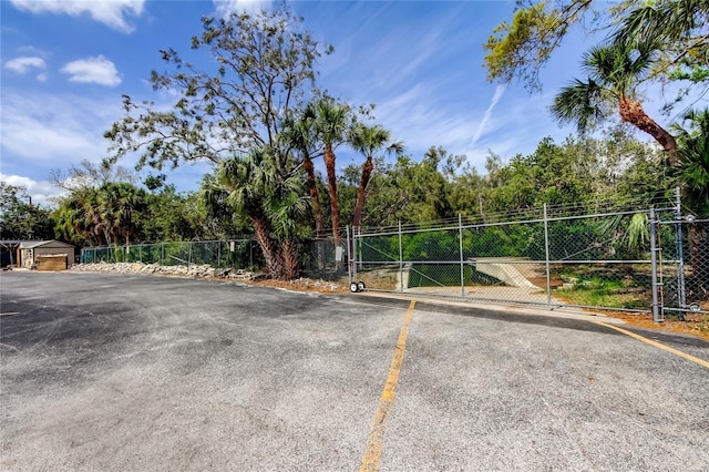 uncovered parking lot featuring a gate and fence