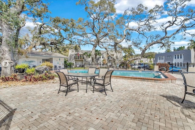 community pool featuring a patio area, a residential view, and fence